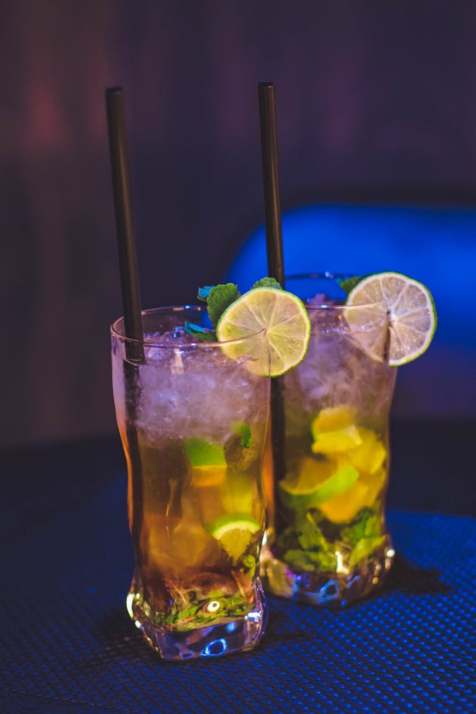 Close-up of refreshing iced citrus cocktails with lime slices and mint, perfect for summer refreshment.